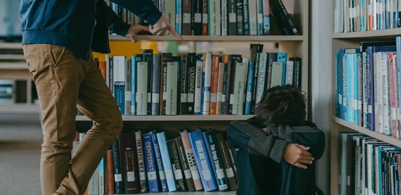 a boy crying on the corner of a school's library due to bad grades