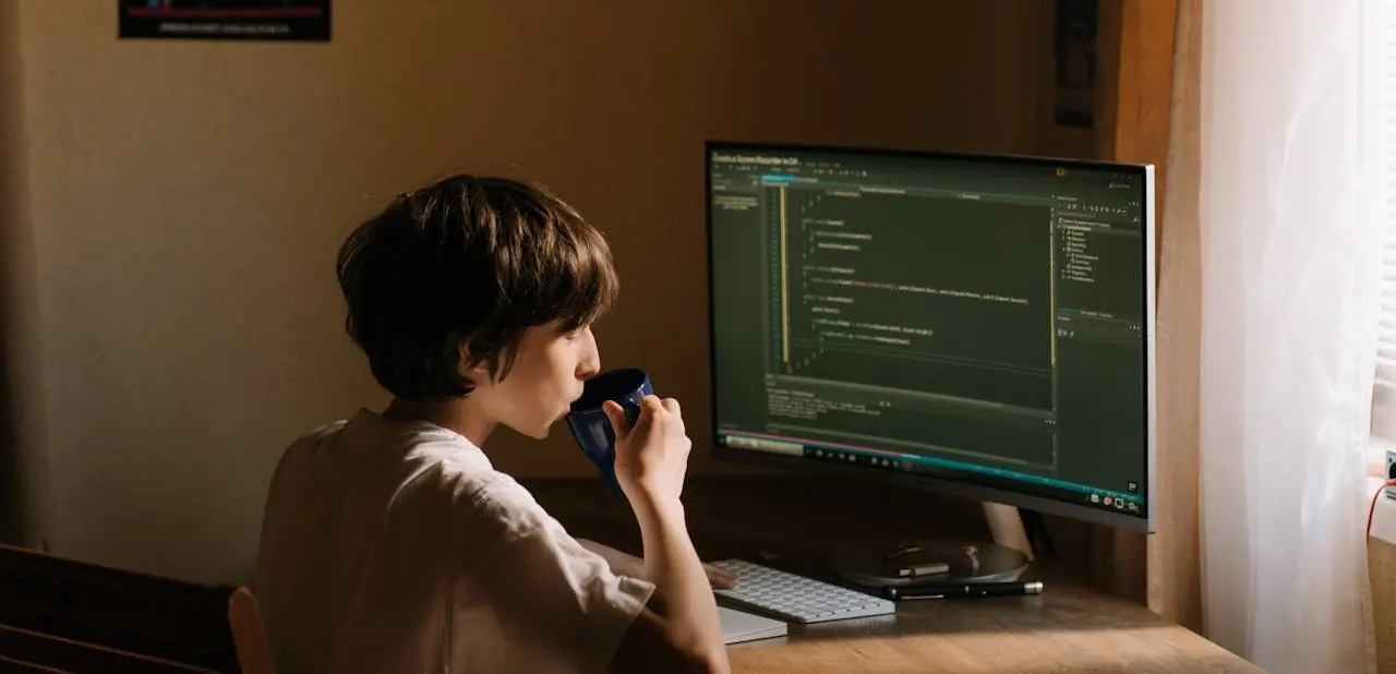 A boy drinking cofee while coding